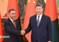 Bangladesh PM Tarique (left) and Chinese President Xi Jinping shaking hands. Behind them there are flags of both countries.