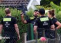 Four police officers are pictured, with one officers holding a gun up