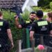 Four police officers are pictured, with one officers holding a gun up