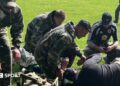 A group including Willy Caballero (left), Aaron Ramsey (second right) and Luke Williams (right) tend to a casualty during a military training exercise as part of the FAW's Uefa pro licence course