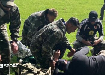A group including Willy Caballero (left), Aaron Ramsey (second right) and Luke Williams (right) tend to a casualty during a military training exercise as part of the FAW's Uefa pro licence course