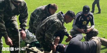 A group including Willy Caballero (left), Aaron Ramsey (second right) and Luke Williams (right) tend to a casualty during a military training exercise as part of the FAW's Uefa pro licence course