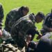 A group including Willy Caballero (left), Aaron Ramsey (second right) and Luke Williams (right) tend to a casualty during a military training exercise as part of the FAW's Uefa pro licence course