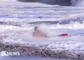 A life guard holds a child in the ocean.