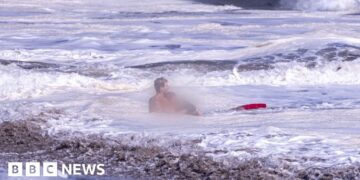 A life guard holds a child in the ocean.