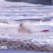 A life guard holds a child in the ocean.