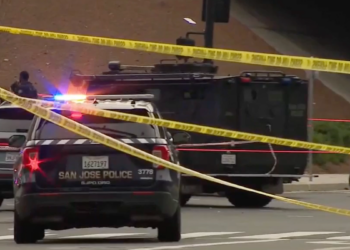 San Jose police vehicles and an armored vehicle block an intersection behind police tape