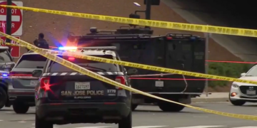 San Jose police vehicles and an armored vehicle block an intersection behind police tape