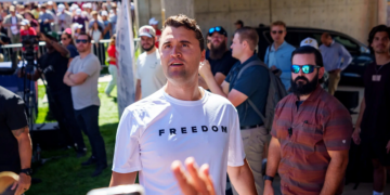Charlie Kirk in a white T-shirt emblazoned with the word