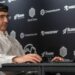 Vladimir Kramnik at a chess tournament in London in August 2024. He sits facing his opponent and is wearing a white shirt and glasses.