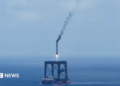 A screengrab of  a Long March 10B booster rocket landing on a recovery platform.