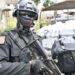 An armed Liberian police officer stands guard beside a truck carrying bags and packages