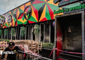 Tables and chairs are covered in ash at the scene of a fatal fire at a bar in Bangkok