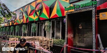 Tables and chairs are covered in ash at the scene of a fatal fire at a bar in Bangkok
