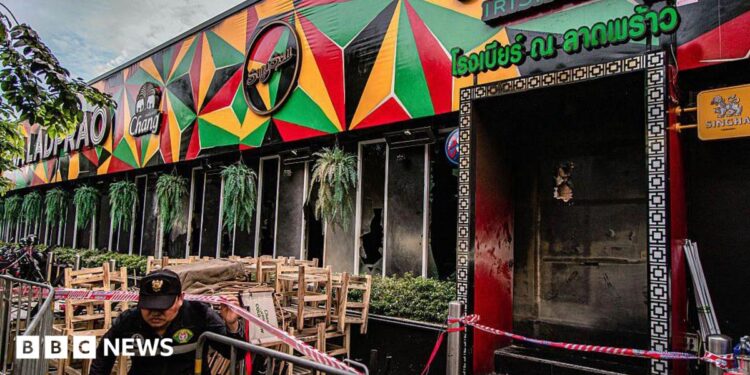 Tables and chairs are covered in ash at the scene of a fatal fire at a bar in Bangkok