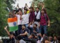 Abhijeet Dipke, head of the Cockroach Janta Party (CJP), celebrates with supporters who stand on an elevated platform holding their hands up in triumph