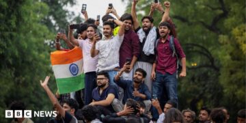 Abhijeet Dipke, head of the Cockroach Janta Party (CJP), celebrates with supporters who stand on an elevated platform holding their hands up in triumph