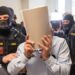 Ex-Syrian intelligence chief Khaled al-Halabi (C) covers his face as he is escorted in handcuffs to the courtroom by justice officers for the trial at the Regional Vienna's Court of Austria.