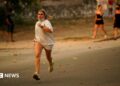 A person runs as the fire spreads in the mountains of Navaluenga, Avila, Spain