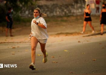 A person runs as the fire spreads in the mountains of Navaluenga, Avila, Spain