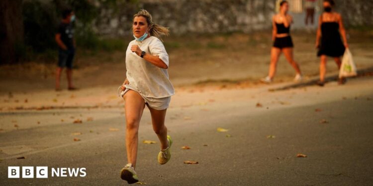 A person runs as the fire spreads in the mountains of Navaluenga, Avila, Spain