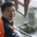 Wang Jibing in an orange polo shirt smiling at the camera