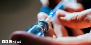 A close up of a person's hands as they prepare an injection