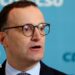 Jens Spahn speaks with German media during a party meeting, he is wearing a black suit and black glasses.