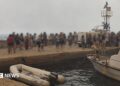 Blurred-out people stand on a marina pier while waiting to be evacuated in Agios Vasileios in Greece.