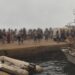Blurred-out people stand on a marina pier while waiting to be evacuated in Agios Vasileios in Greece.