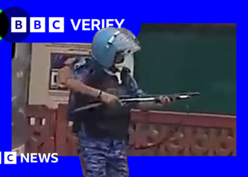 A still from a video of a rapid action force officer in Delhi, raising what experts say is a pellet gun.