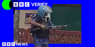 A still from a video of a rapid action force officer in Delhi, raising what experts say is a pellet gun.