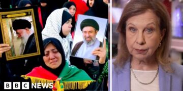 A lady who is crying holding up two pictures. On the right, Lyse Doucet