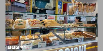 Food stall in Napoli with shelves stocked with sandwiches, pasta, bread, and fried foods