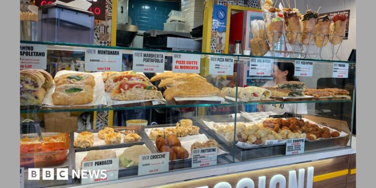 Food stall in Napoli with shelves stocked with sandwiches, pasta, bread, and fried foods