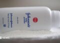 A bottle of Johnson and Johnson Baby Powder is seen in a photo illustration placed on its side on top of some white baby powder