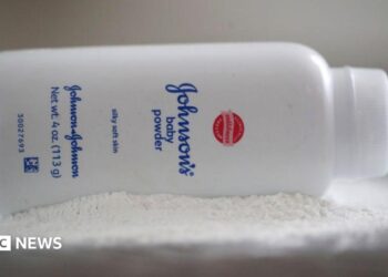 A bottle of Johnson and Johnson Baby Powder is seen in a photo illustration placed on its side on top of some white baby powder