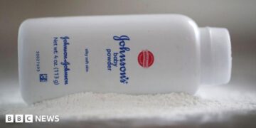 A bottle of Johnson and Johnson Baby Powder is seen in a photo illustration placed on its side on top of some white baby powder