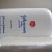 A bottle of Johnson and Johnson Baby Powder is seen in a photo illustration placed on its side on top of some white baby powder