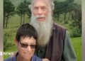 Rodney Saunders stands behind Rachel. Rodney has a long grey beard while Rachel has dark hair and is wearing sunglasses