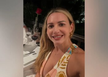 Judge Ashlee Cole smiles while seated at a restaurant table with a glass of red wine and a rose in front of her.