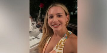 Judge Ashlee Cole smiles while seated at a restaurant table with a glass of red wine and a rose in front of her.