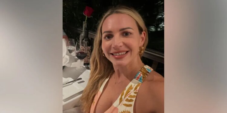Judge Ashlee Cole smiles while seated at a restaurant table with a glass of red wine and a rose in front of her.