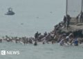 People in the water swimming, group of people climbing rocks