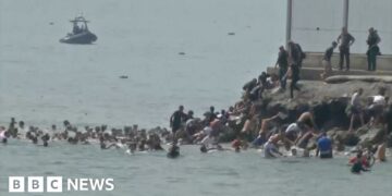 People in the water swimming, group of people climbing rocks