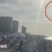 Jet flying above a crowd on a beach with a red circle around it.