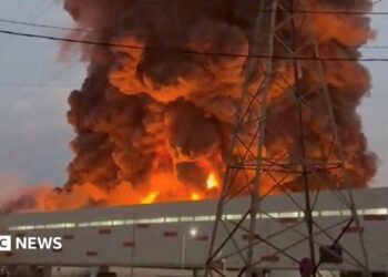 A fire ball rises above a low, light-coloured building.