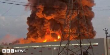 A fire ball rises above a low, light-coloured building.