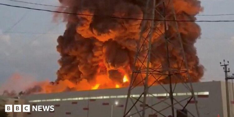 A fire ball rises above a low, light-coloured building.