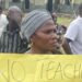 A woman holds up a banner at a protest at a school.